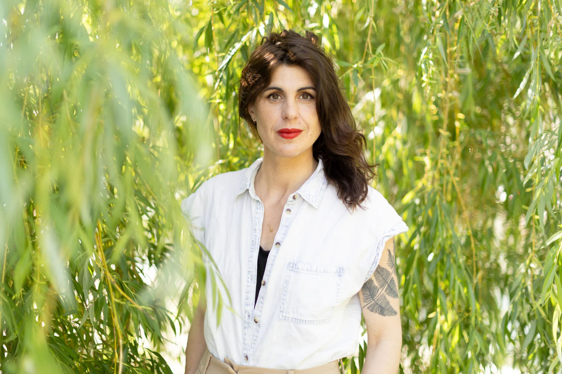 une femme habillée en blanc pose entre des arbres 